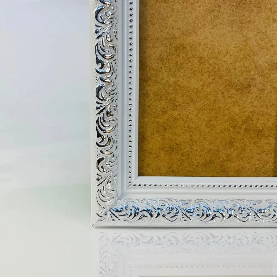 Decorative silver picture frame with intricate detailing and a blank background inside.